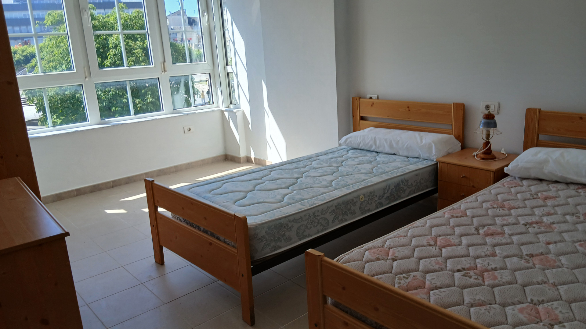 Twin-bed hostel room with street-facing bay windows