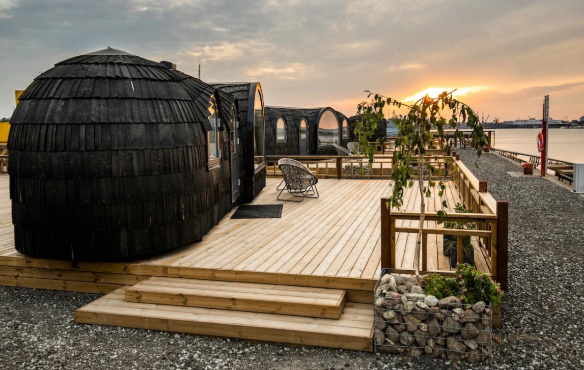 Black-shingled iglus on a wooden deck at dusk