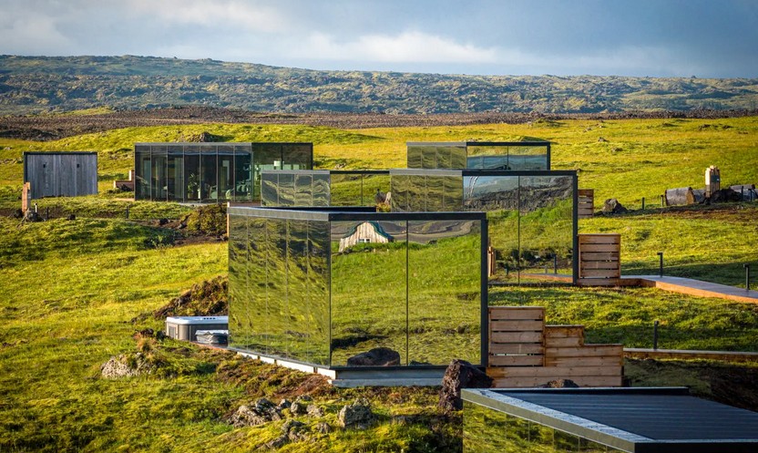 Cluster of mirrored cabins in a wide green field