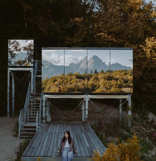 Mirrored cabin reflecting a mountain on a wooden deck